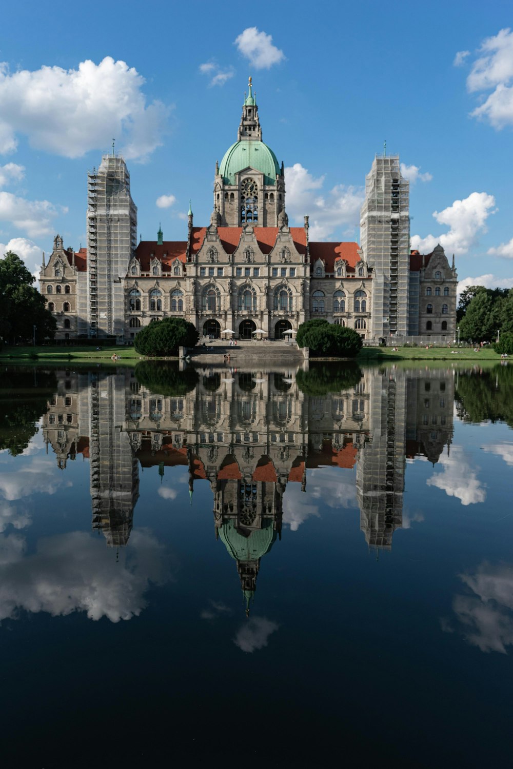 a large building with towers and a pond in front of it