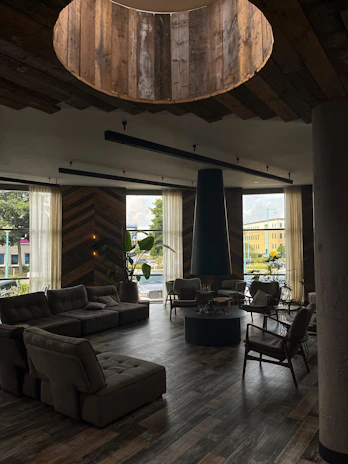 A cozy, sunlit common lounge area with comfortable seating and plants, reflecting a welcoming coliving vibe.