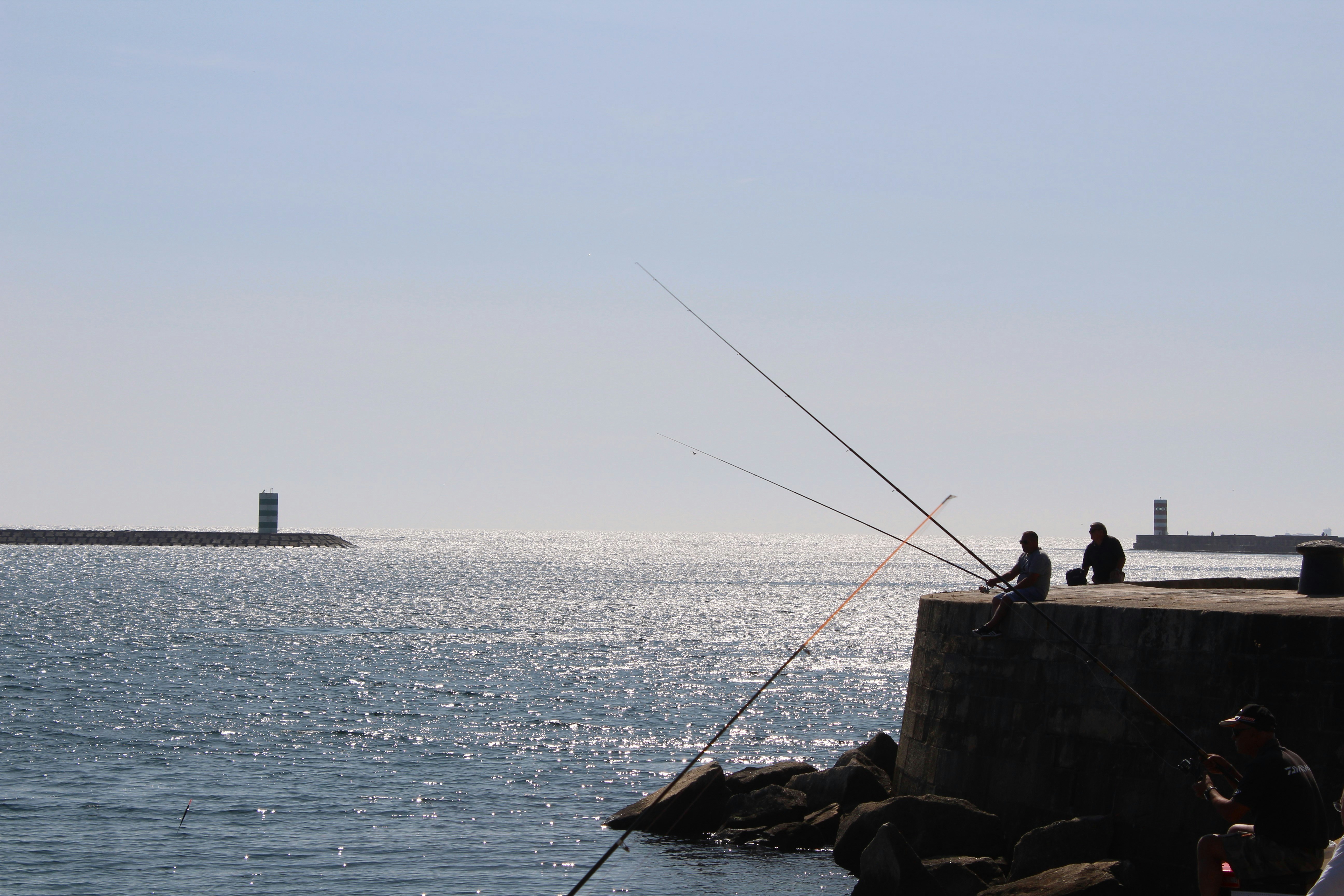 a fishing pole on a dock, Fishing from the lighthouse pontoon in Foz do Douro.