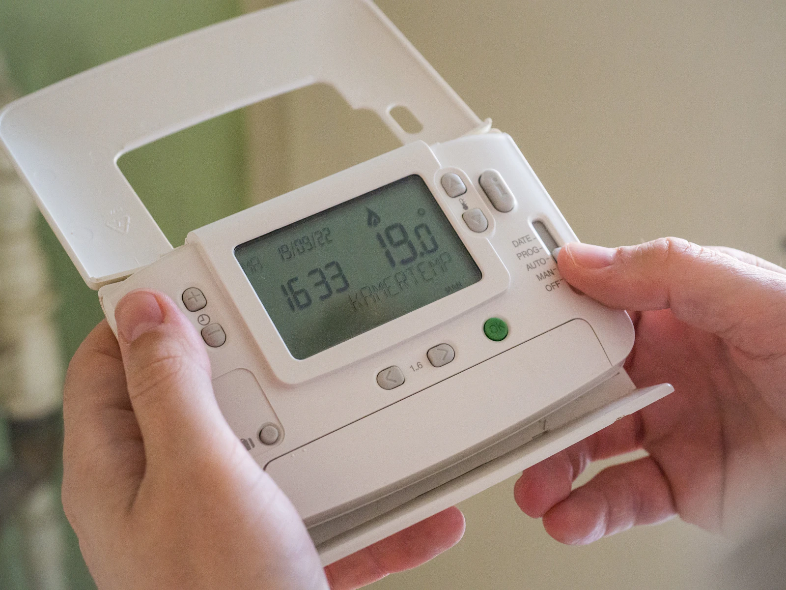 A person holding and adjusting a smart home device