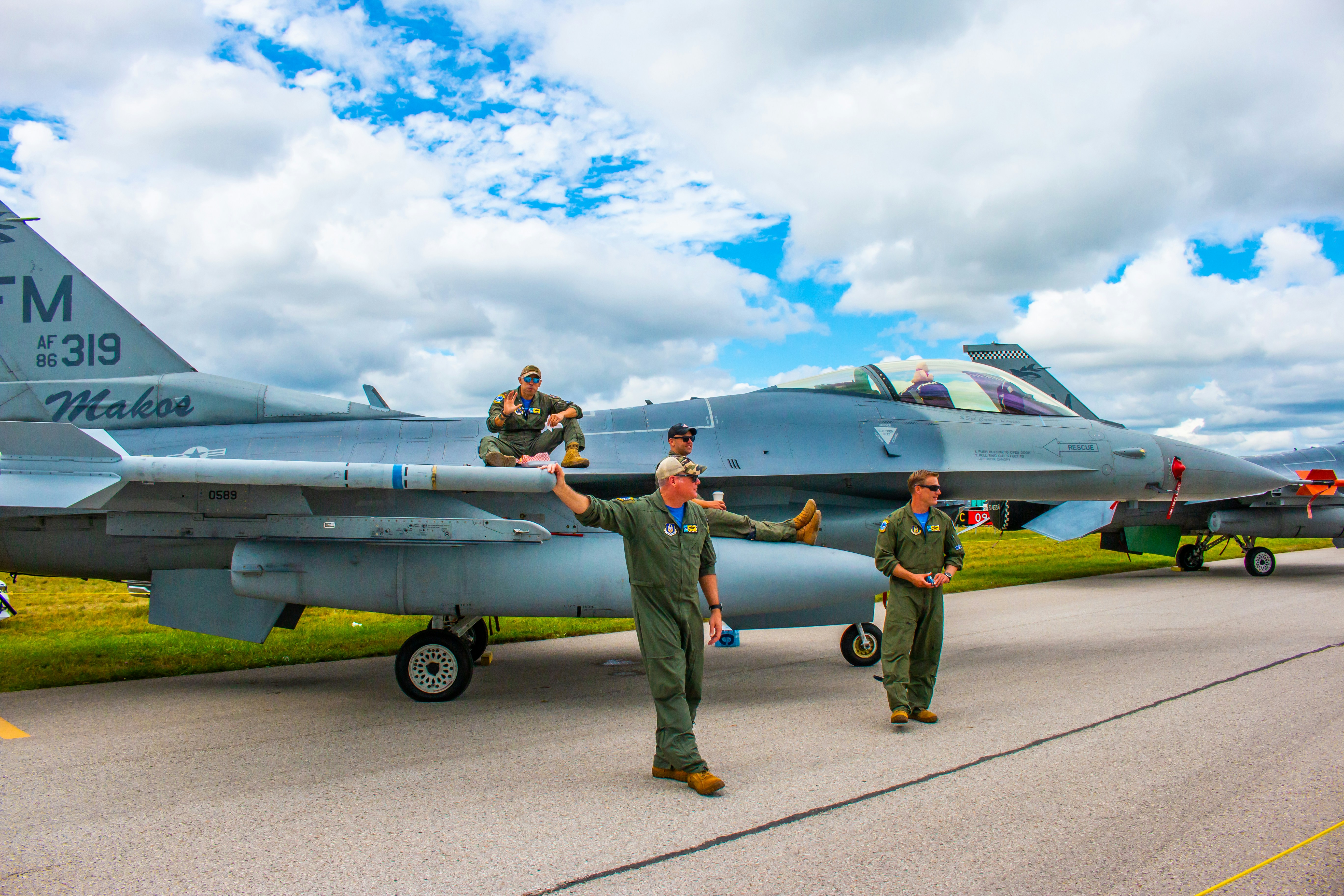 a group of men standing next to a fighter jet