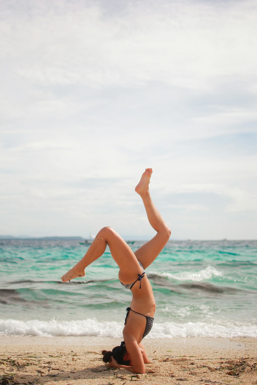 a woman doing a handstand on a beach