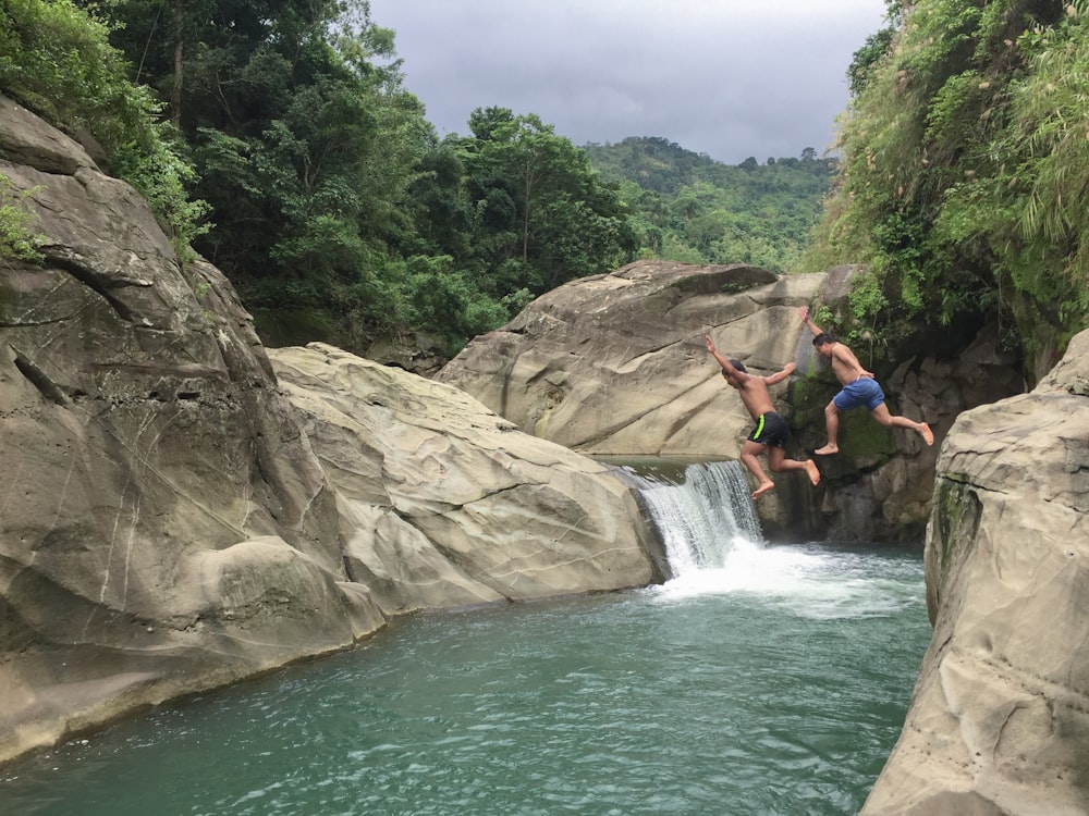 a couple of people jumping into a river