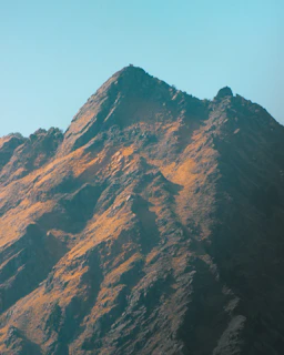 A rugged mountain peak at dawn with soft light highlighting its sharp edges, symbolizing strength and endurance.