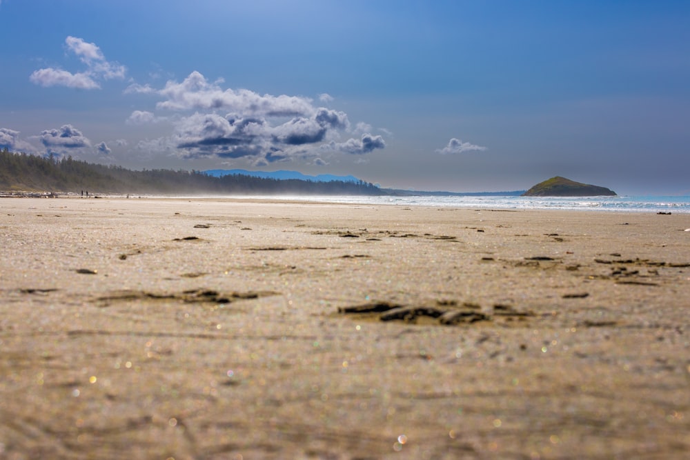 a sandy beach with a rock in the distance