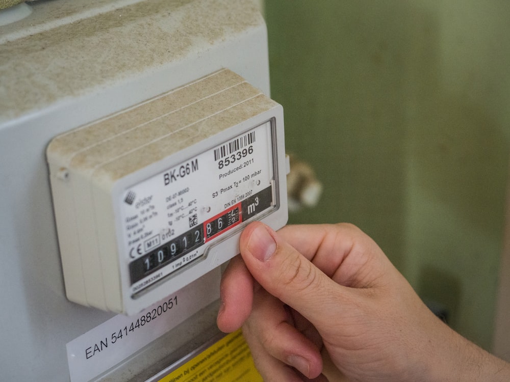 a hand holding a white box with a black and red label