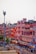 A vibrant market street in Jaipur, India, featuring traditional Rajasthani architecture with pink and red buildings illuminated by warm lighting. The street is bustling with people, vehicles, and shops creating an energetic urban atmosphere.