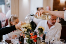 a person pouring wine into a glass