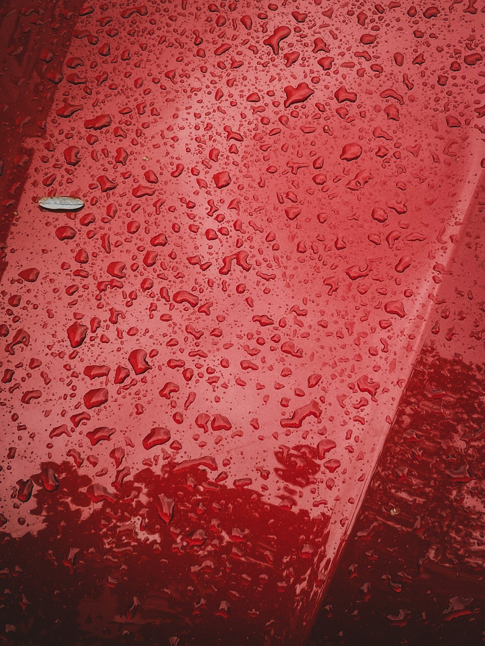 a red surface with water droplets