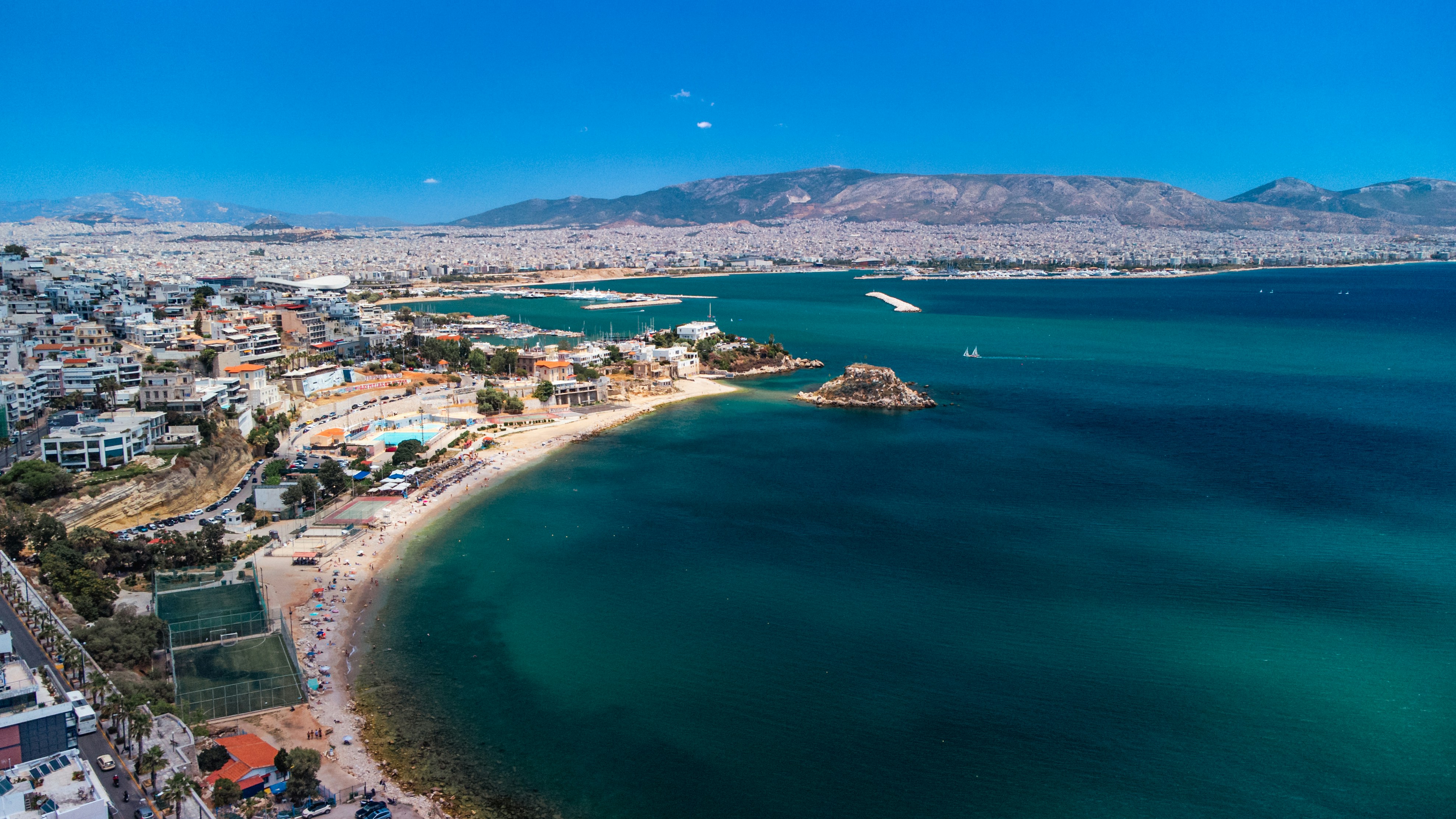 a beach with blue water and a city on the other side