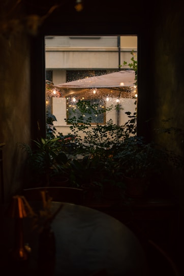 Comfortable garden room with warm lighting and a view of vibrant plants outside.