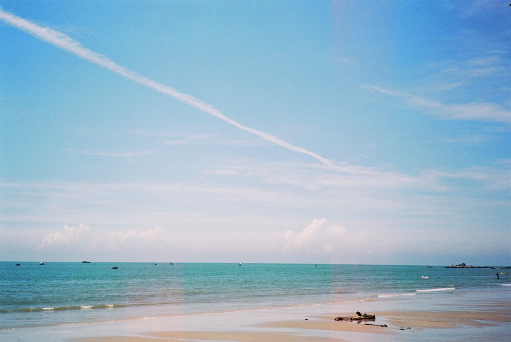 a beach with blue water and a blue sky