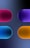 Four pill-shaped objects, each with a distinct gradient and color, are organized with two on the top and two on the bottom against a dark, gradient background. The shapes are glossy and three-dimensional, creating a soothing and futuristic aesthetic.