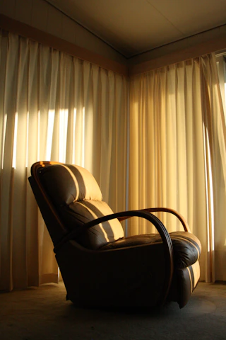 A serene corner of the spa with plush chairs, warm lighting, and delicate white curtains fluttering gently.