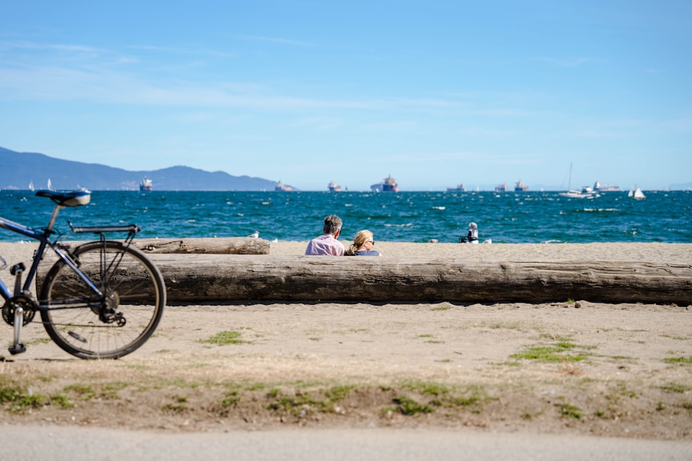 a bicycle parked on a log next to a body of water