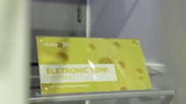 A sign is displayed with yellow and white colors featuring the text 'ELETRONIC TEMP. CONTROL' along with 'Soft Touch Digital Display.' The background has a soft yellow hue with circular patterns resembling bubbles or holes. The brand 'Homa' is visible along with a 20th-anniversary symbol.