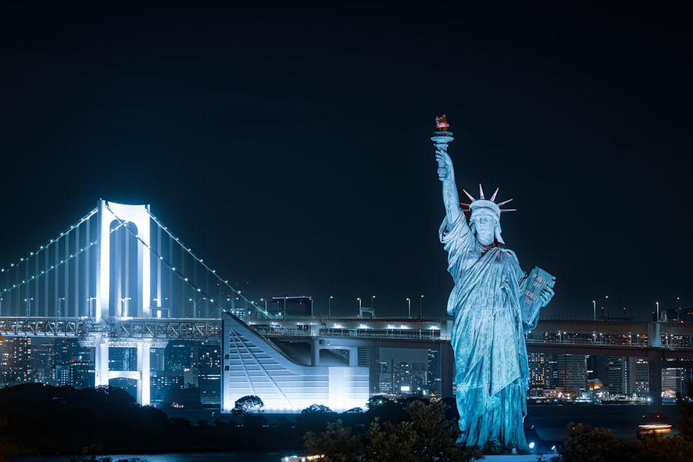 a statue of a person holding a torch in front of a bridge