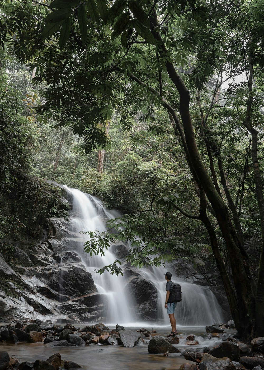 a person standing on a rock near a waterfall