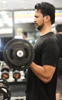 Close-up of a person lifting a heavy dumbbell in a bright home gym.