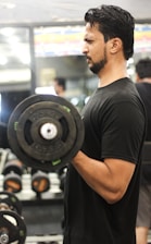 A focused person lifting weights in a bright home gym setting.