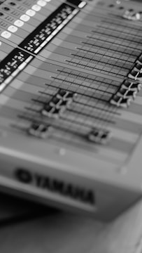 A close-up view of a sound mixing console with multiple sliders and buttons, featuring a clear brand logo.