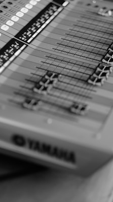 A close-up view of a sound mixing console with multiple sliders and buttons, featuring a clear brand logo.