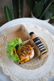 A warm, inviting photo of a traditional Indonesian meal packed neatly in eco-friendly takeaway containers.