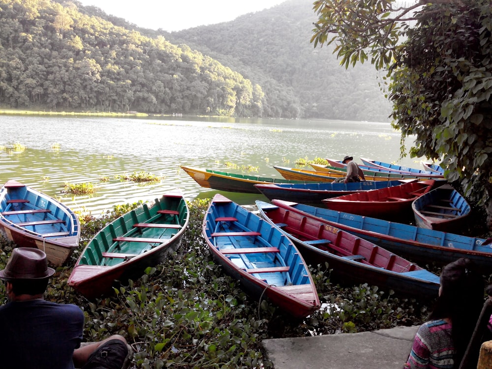 a group of boats sit on the shore of a lake