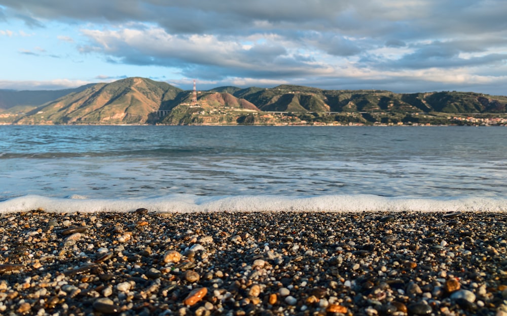 a rocky beach with a lighthouse in the distance