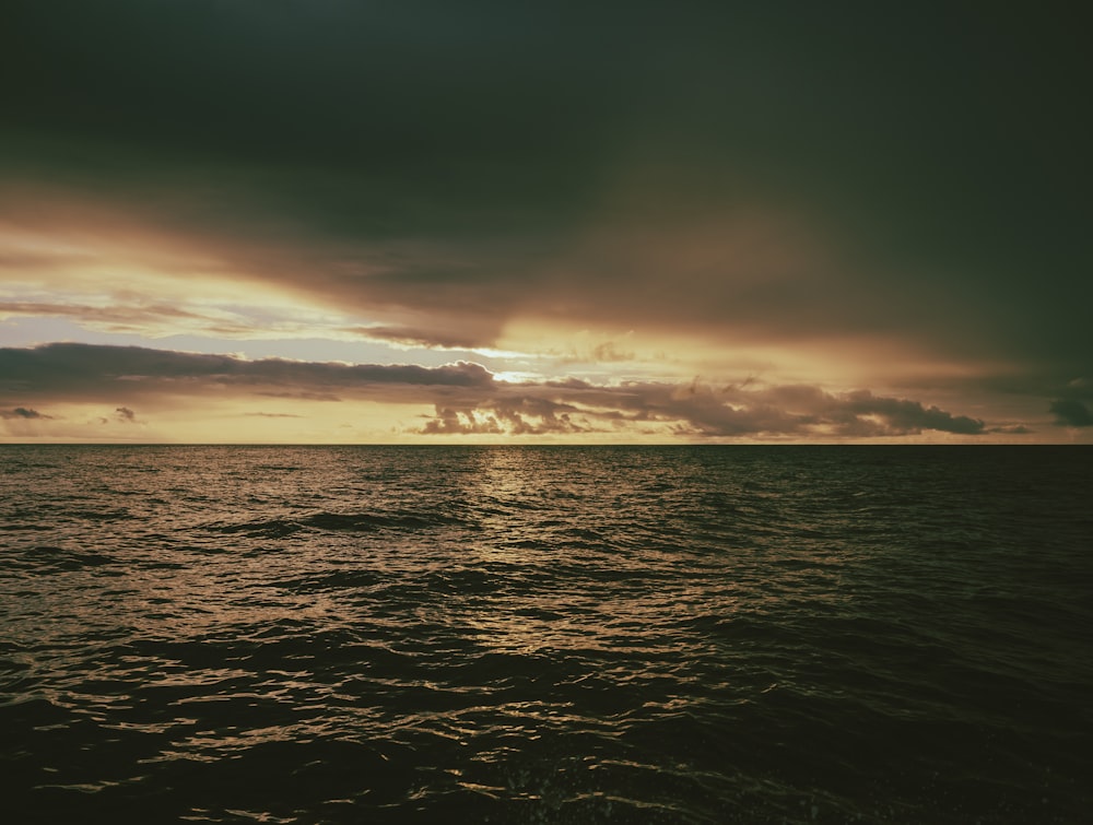 a body of water with a cloudy sky above it