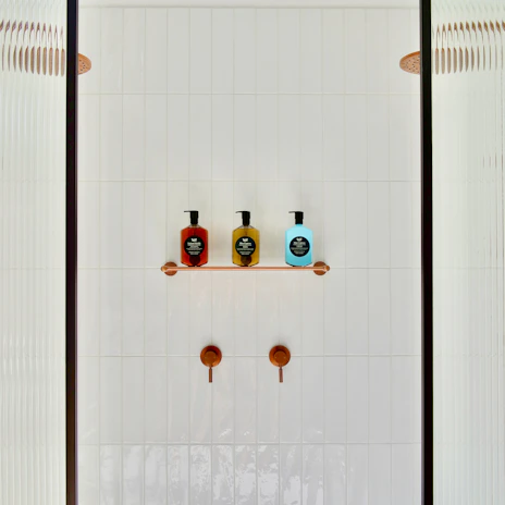 Close-up of a custom glass shower system with polished aluminum fixtures.