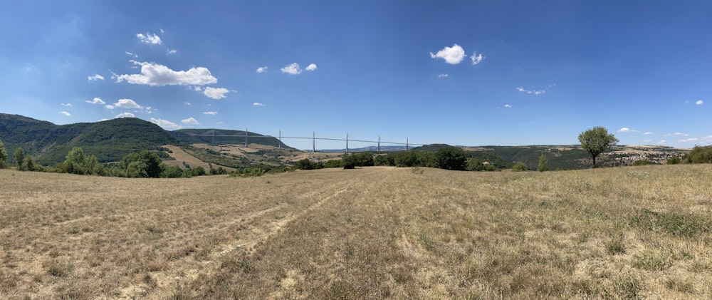 a large field with trees and hills in the background