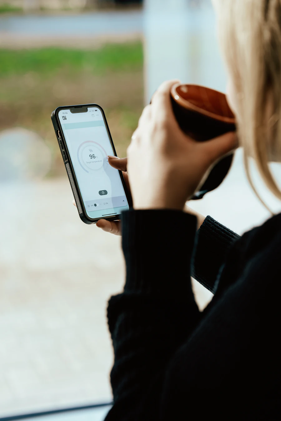Iemand met een telefoon en een kop koffie