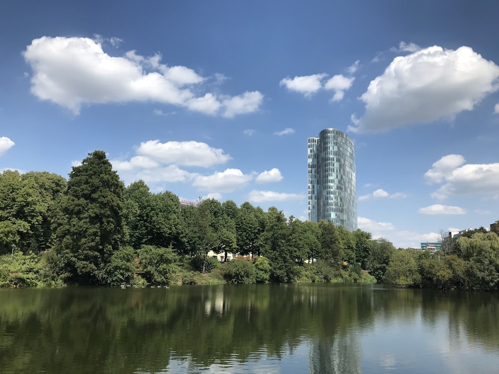 a body of water with trees and a tall building in the background