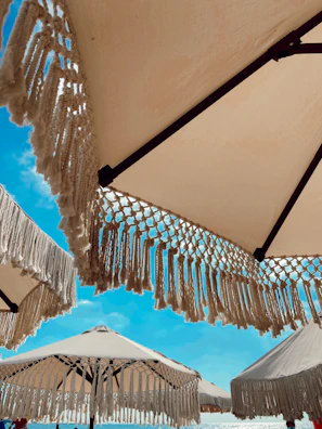 Elegant beach umbrellas casting shadows on the smooth sand, with the soft blue sea stretching beyond.