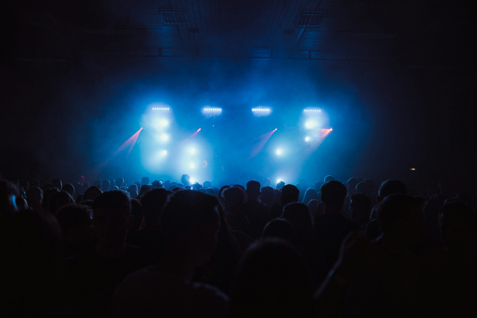 Nighttime crowd at an outdoor music festival, lit stage in the background