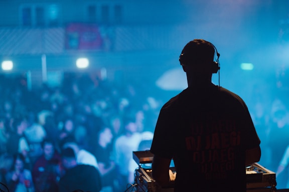 A vibrant DJ spinning tracks with colorful lights and a lively crowd dancing.