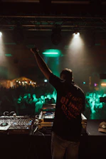 a man holding a microphone in front of a dj booth