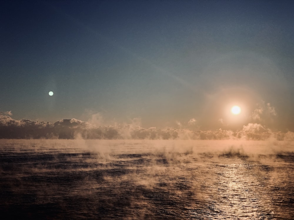 a body of water with a moon in the sky above it