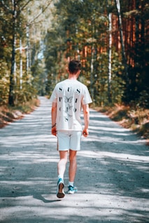 A soft cotton t-shirt laid out flat, showcasing a vibrant forest trail graphic with motivational text.