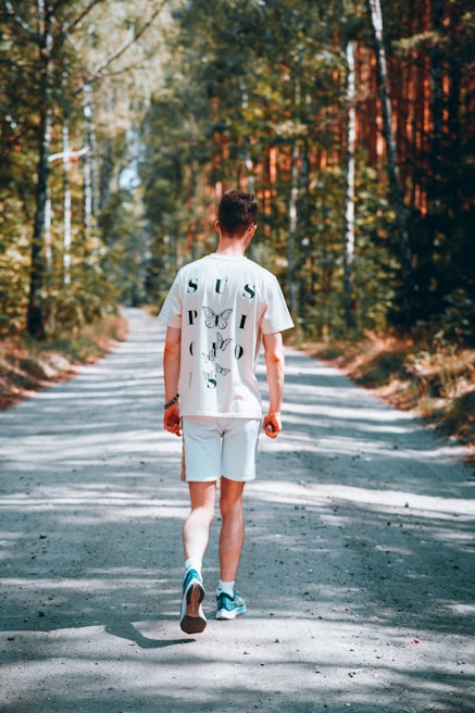 A soft cotton t-shirt laid out flat, showcasing a vibrant forest trail graphic with motivational text.