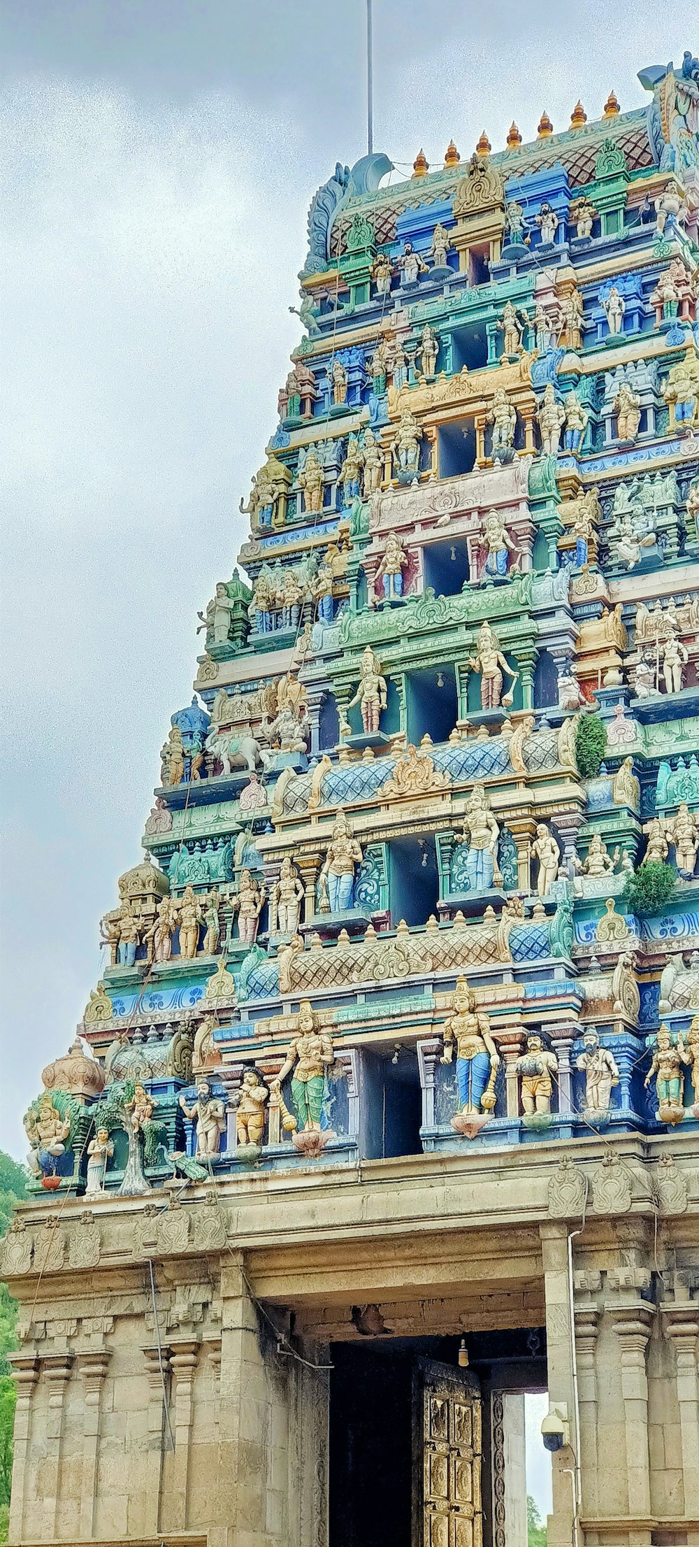 a large ornate building with statues with Ranganathaswamy Temple, Srirangam in the background