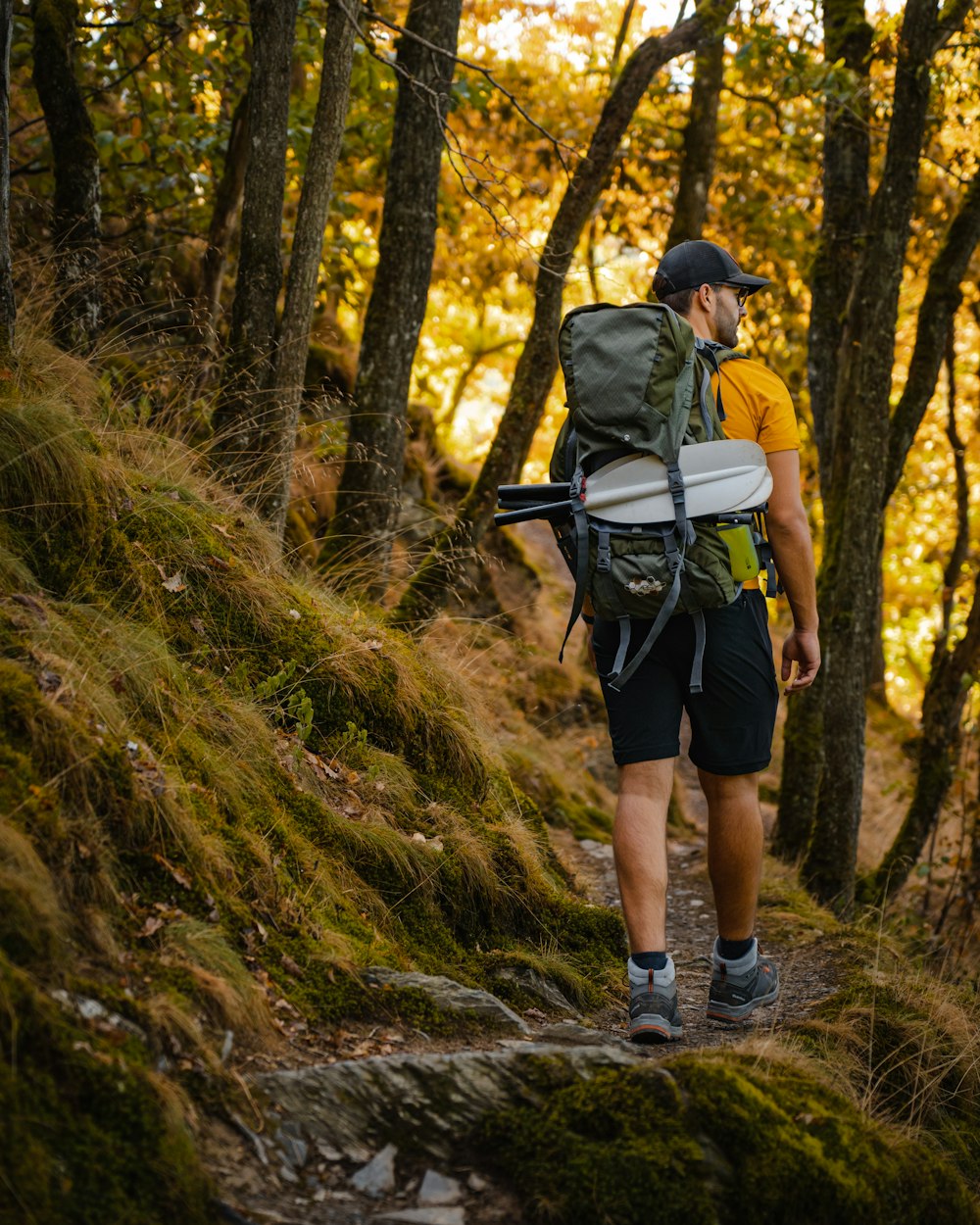 a man with a backpack walking on a trail in the woods