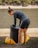 Man inflating a portable surfboard near a rocky shoreline