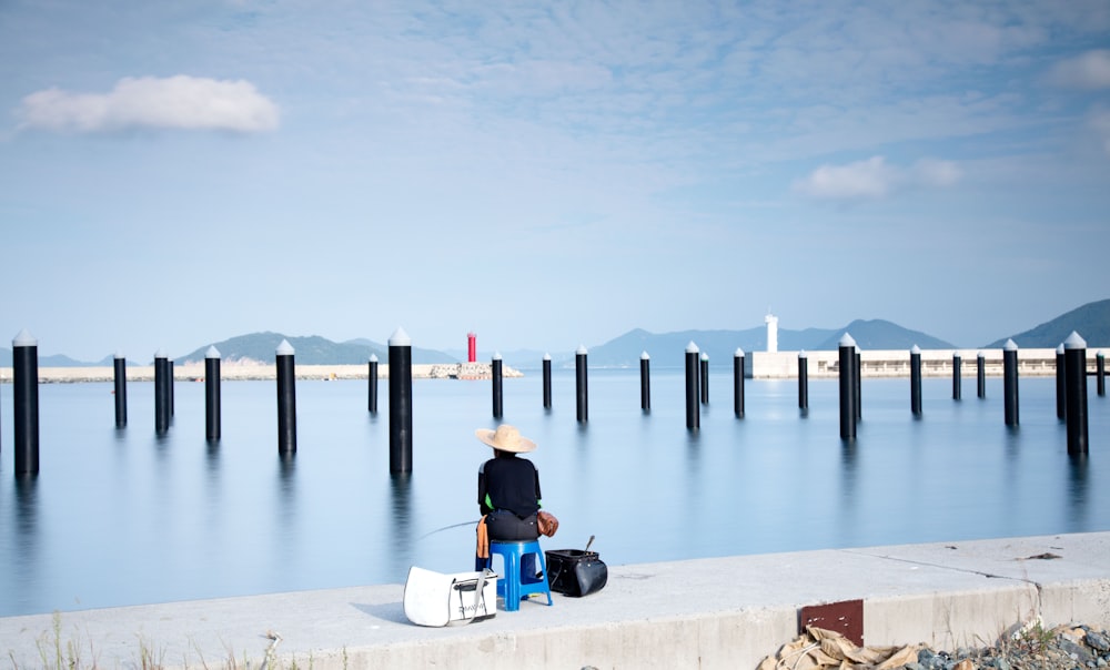 a person sitting on a bench by a body of water