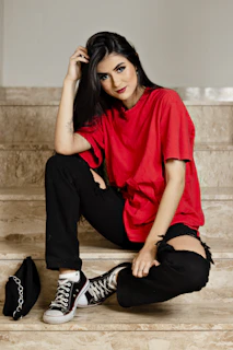 A relaxed model sitting on city steps wearing an oversized t-shirt paired with slim-fit jeans, blending comfort and edge.