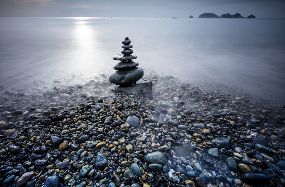 a rocky beach with a statue on top of it