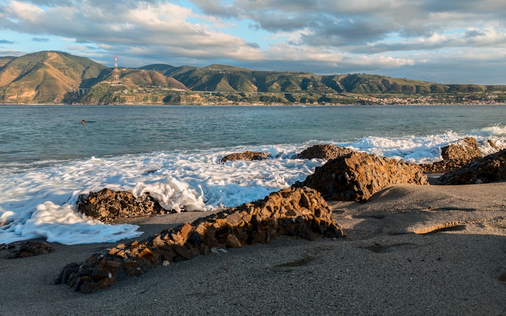 a rocky beach with a lighthouse in the distance