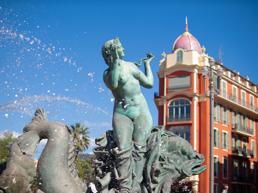 a statue of a person with a beard and a red building in the background