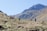 A group of diverse travelers enjoying a scenic landscape with mountains and a blue sky.